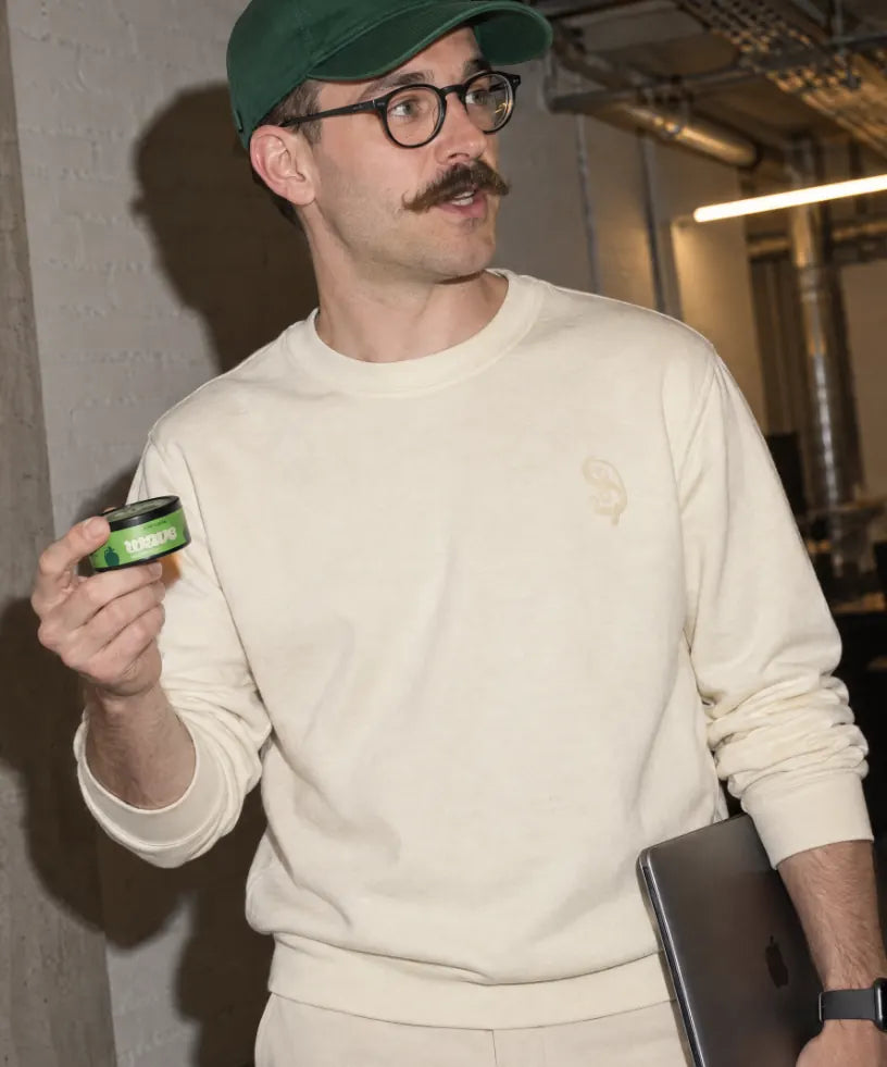 Man in a cream sweater holding a can of WAVE